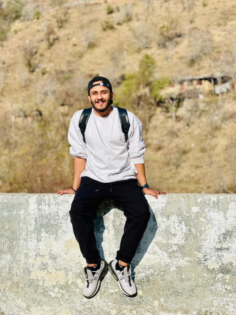 Traveler sitting outdoors with a backpack and mountain landscape in the background